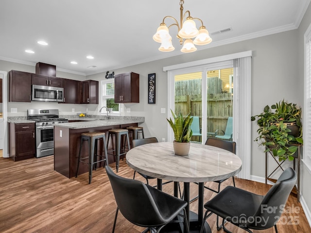 dining space with crown molding, recessed lighting, a chandelier, and light wood-style floors