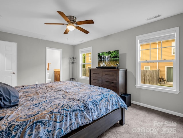 carpeted bedroom with visible vents, a ceiling fan, baseboards, and ensuite bathroom