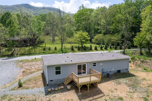 rear view of property featuring a deck with mountain view, stairway, crawl space, a view of trees, and central air condition unit