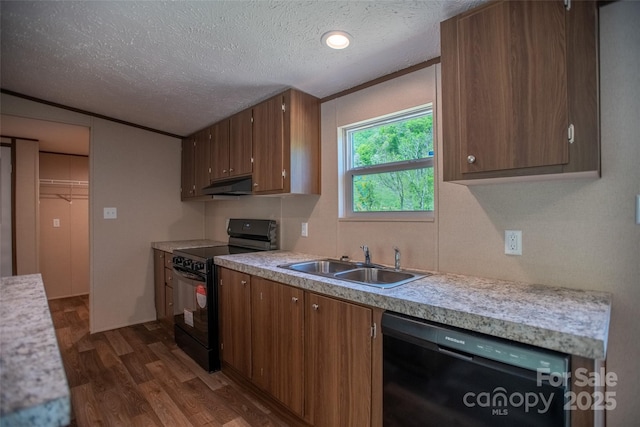 kitchen featuring light countertops, under cabinet range hood, a sink, dark wood finished floors, and black appliances