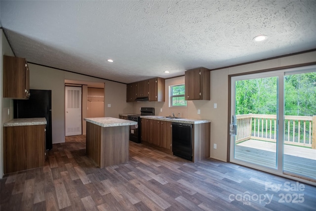 kitchen featuring a sink, light countertops, a textured ceiling, a center island, and black appliances