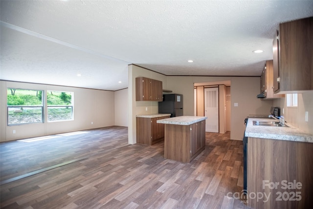 kitchen featuring brown cabinets, light countertops, freestanding refrigerator, open floor plan, and a kitchen island