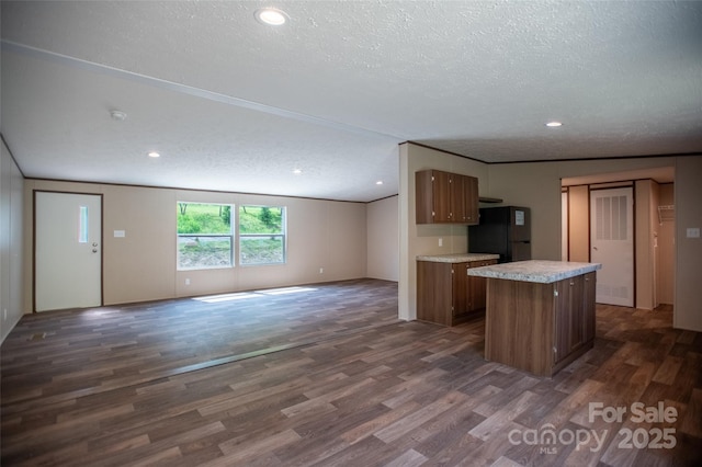 kitchen featuring dark wood-type flooring, freestanding refrigerator, a textured ceiling, and open floor plan