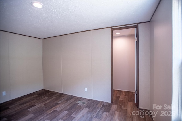 unfurnished room featuring a textured ceiling, visible vents, and wood finished floors