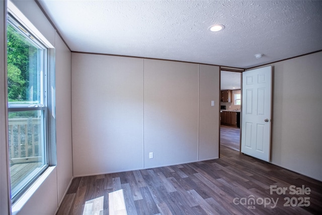 unfurnished room featuring a textured ceiling, plenty of natural light, and wood finished floors