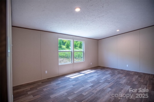unfurnished room with a textured ceiling, wood finished floors, and a decorative wall