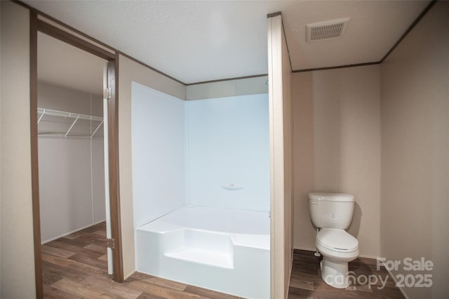 full bathroom with a washtub, toilet, visible vents, and wood finished floors