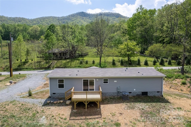 rear view of property with crawl space, a deck with mountain view, cooling unit, and a forest view