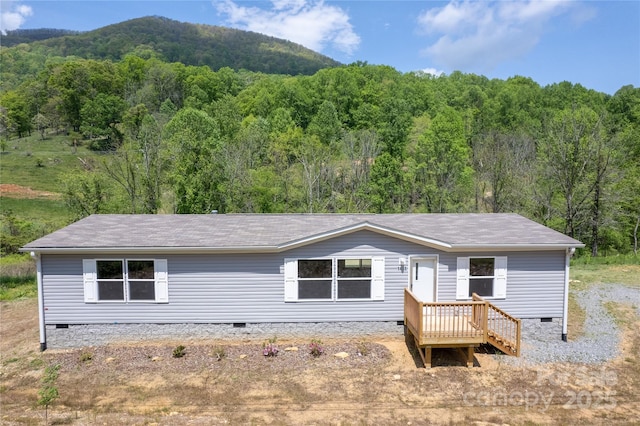 view of front of house with roof with shingles, a forest view, a mountain view, and crawl space
