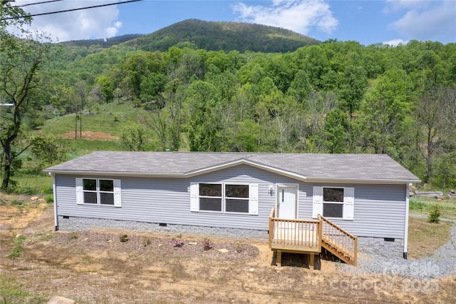 view of front of home with roof with shingles, a mountain view, crawl space, and a forest view