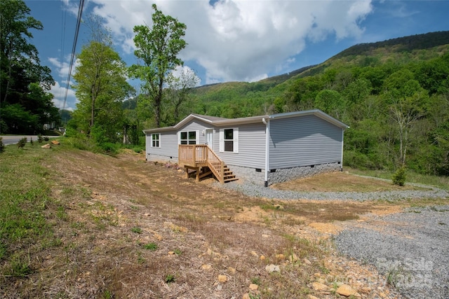 view of front of house with a wooded view, a mountain view, and crawl space