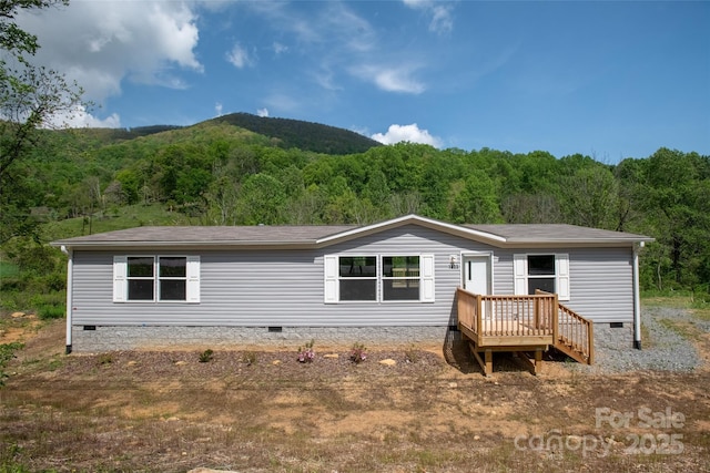 back of house with crawl space and a view of trees