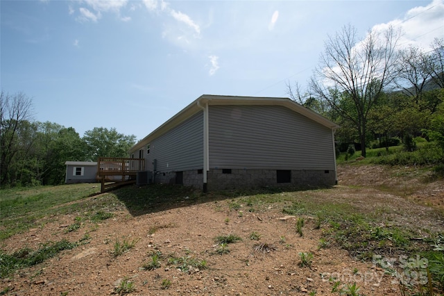 view of side of home with central AC, crawl space, and a deck