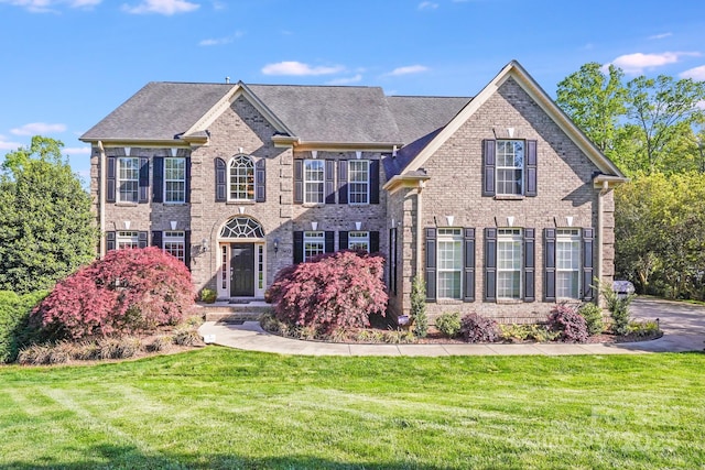 colonial-style house featuring brick siding and a front yard