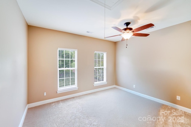 carpeted spare room with baseboards, a ceiling fan, attic access, and visible vents