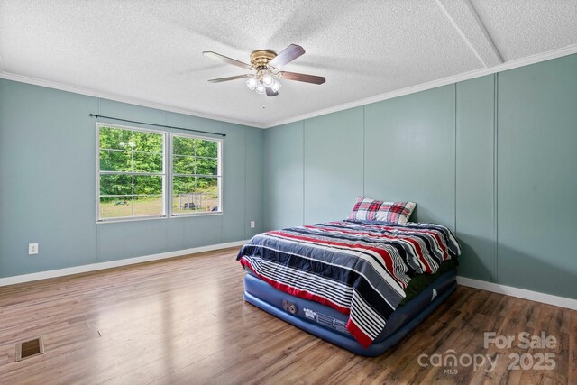 2521 Melvin Propst Dr, Morganton, NC 28655 - bedroom featuring a textured ceiling, ornamental molding, a decorative wall, wood finished floors, and ceiling fan
