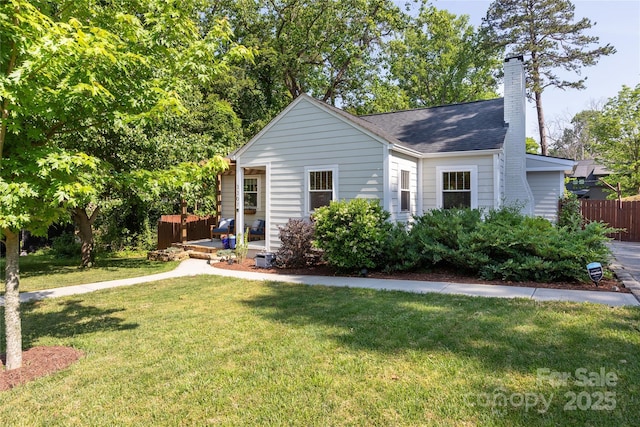 view of front of house featuring fence, a chimney, a shingled roof, and a front yard