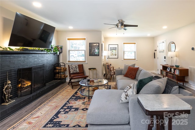 living room with a fireplace, ceiling fan, a healthy amount of sunlight, and wood finished floors
