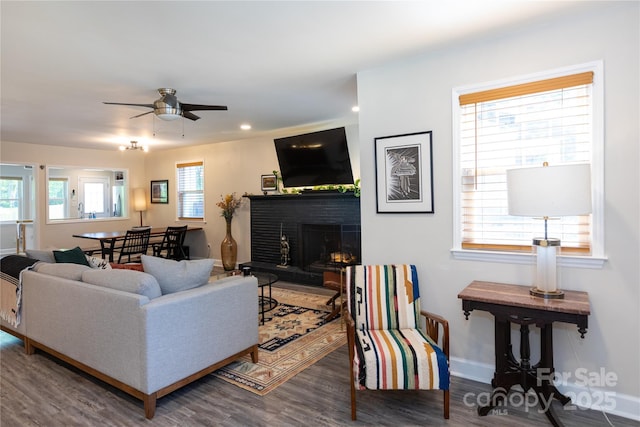 living area featuring a brick fireplace, wood finished floors, baseboards, ceiling fan, and recessed lighting