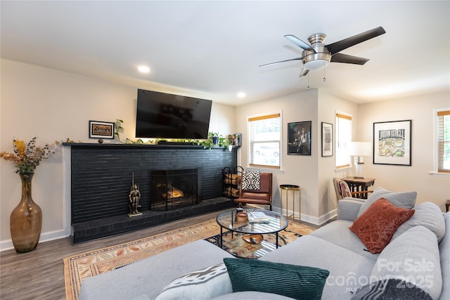 living room featuring baseboards, ceiling fan, wood finished floors, and a healthy amount of sunlight