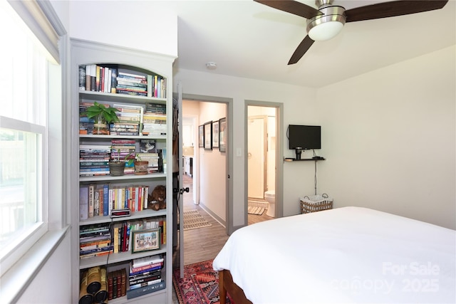 bedroom featuring ceiling fan, ensuite bath, and wood finished floors