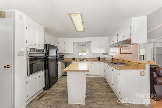 5013 Friendship Circle Rd, East Bend, NC 27018 - kitchen with black appliances, under cabinet range hood, a peninsula, wood finished floors, and white cabinetry
