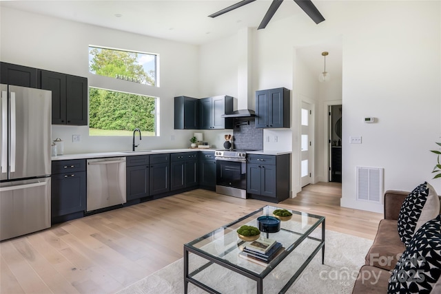 kitchen with visible vents, a towering ceiling, light countertops, a sink, and appliances with stainless steel finishes