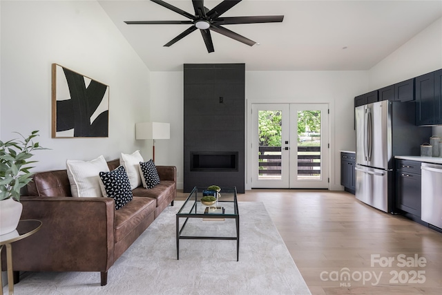 living area featuring ceiling fan, french doors, lofted ceiling, and light wood-type flooring