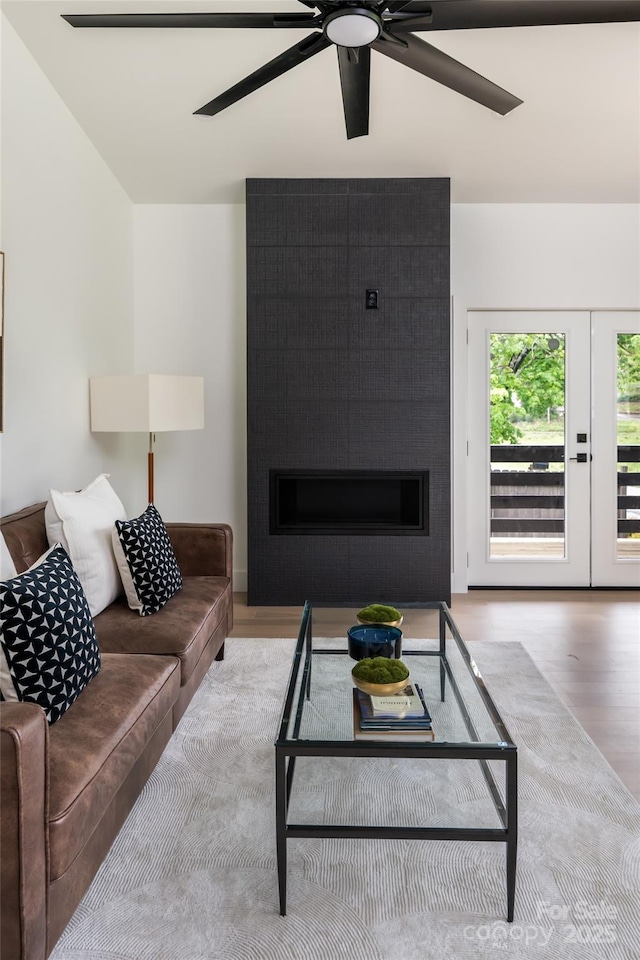 living area featuring ceiling fan, wood finished floors, and a fireplace