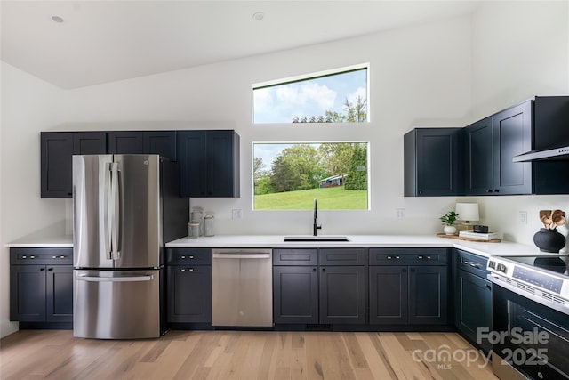 kitchen with light countertops, stainless steel appliances, a sink, and light wood-style floors