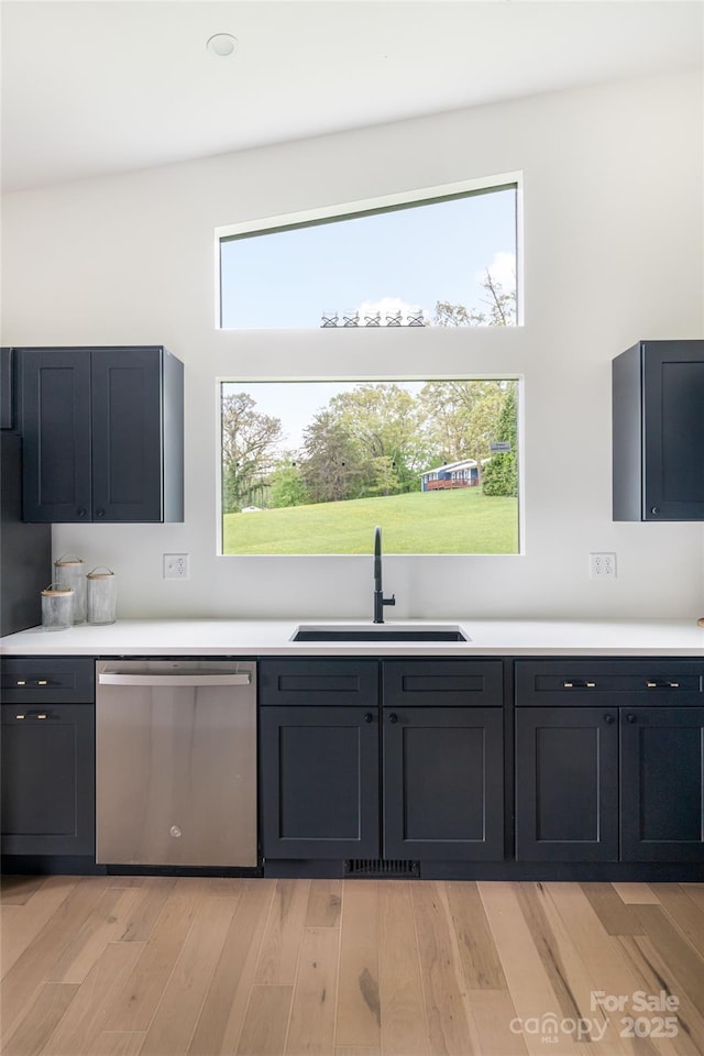 kitchen featuring a sink, dishwasher, light countertops, light wood-type flooring, and visible vents