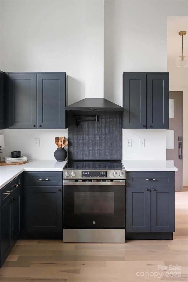 kitchen featuring light wood-style floors, stainless steel electric range, wall chimney range hood, and tasteful backsplash