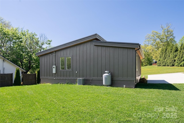 view of side of property featuring fence, central air condition unit, board and batten siding, and a yard