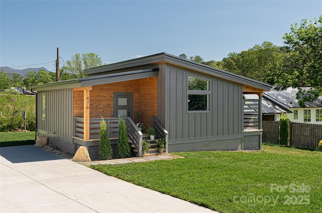 view of front of home featuring board and batten siding, fence, and a front lawn