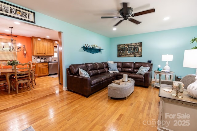 living room featuring recessed lighting, light wood finished floors, and ceiling fan with notable chandelier