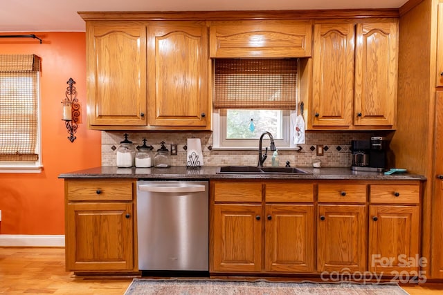 kitchen with stainless steel dishwasher, a sink, baseboards, and tasteful backsplash