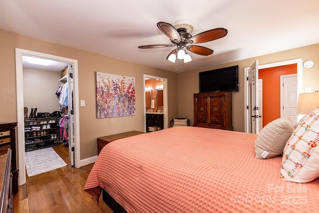 bedroom featuring ceiling fan, wood finished floors, a closet, connected bathroom, and a spacious closet
