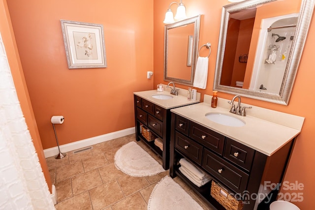 bathroom featuring baseboards, two vanities, a sink, and tile patterned floors