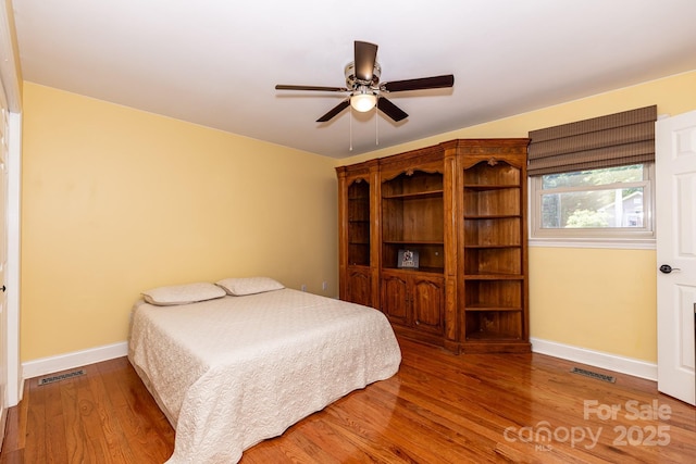 bedroom featuring baseboards, a ceiling fan, wood finished floors, and visible vents