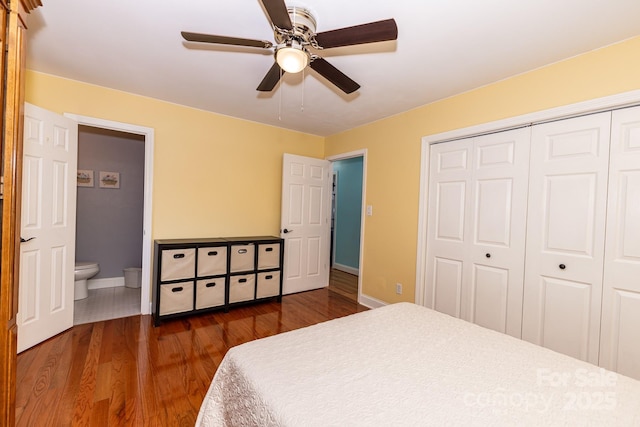 bedroom featuring ceiling fan, dark wood finished floors, baseboards, ensuite bathroom, and a closet