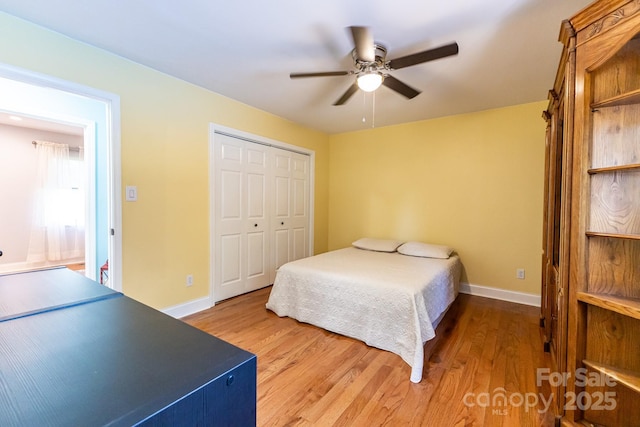 bedroom with baseboards, a ceiling fan, wood finished floors, and a closet