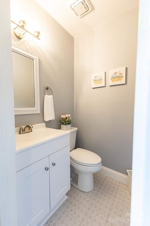 bathroom with vanity, baseboards, toilet, and visible vents