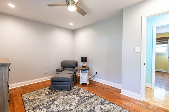 sitting room with light wood-style floors, a ceiling fan, and baseboards