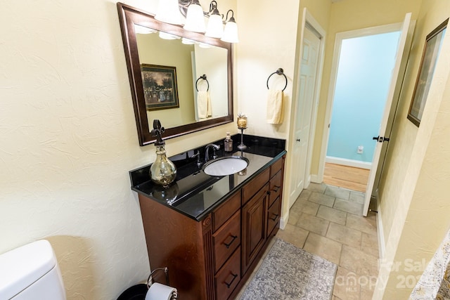 bathroom with toilet, baseboards, and vanity