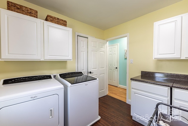 laundry room with baseboards, dark wood-style floors, cabinet space, and washing machine and clothes dryer