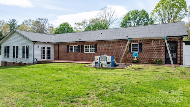 rear view of house with a lawn, roof with shingles, and brick siding