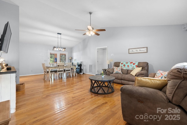 living area featuring visible vents, light wood finished floors, ceiling fan, and vaulted ceiling