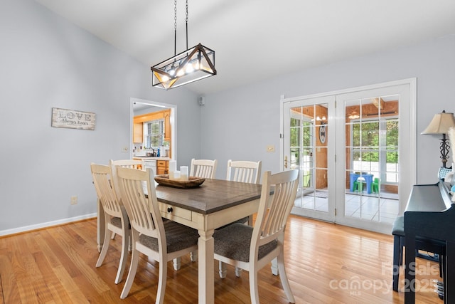 dining area featuring an inviting chandelier, baseboards, french doors, and light wood-type flooring
