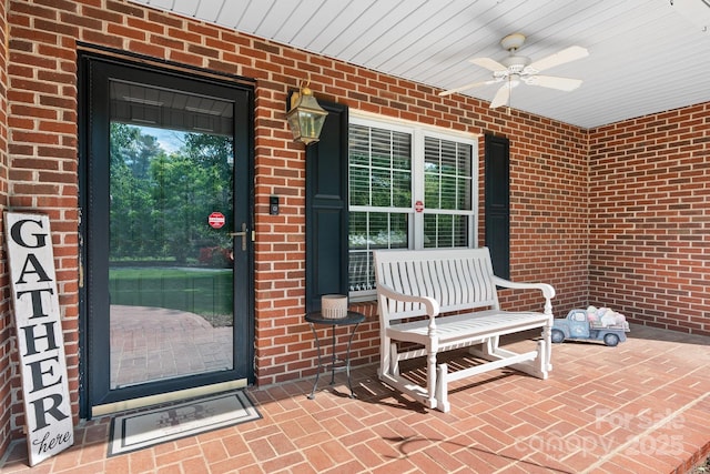 property entrance featuring brick siding, ceiling fan, and covered porch