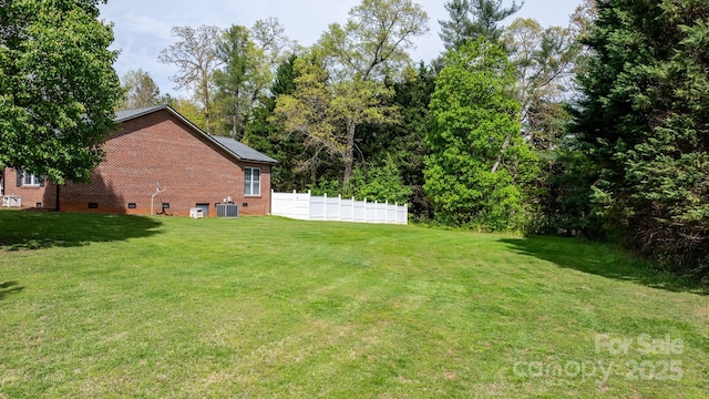 view of yard with central air condition unit and fence
